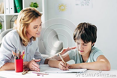 Kid with dyslexia drawing with pencil and child psychologist Stock Photo