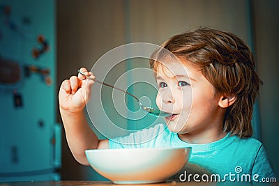 Kid eating. Little boy having breakfast in the kitchen. Parenthood. Happy child. Young kid sitting on the table eating Stock Photo