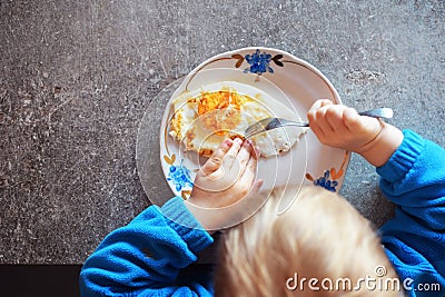 Kid eats fried egg with fork Stock Photo