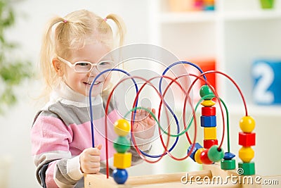 Kid in eyeglases playing colorful toy in home Stock Photo