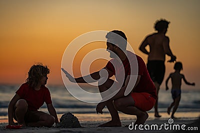 Kid and father building sandcastle. Father and son playing on the beach. Father and child son playing in the sand on Stock Photo