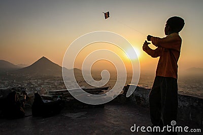 Kid flying his kite at sunset at the Pap Mochani Gayatri Temple, Pushkar, Rajasthan, India Stock Photo