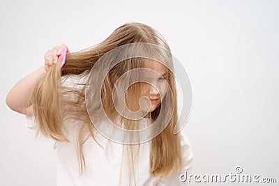 kid girl combs long and tangled hair. white background. Stock Photo