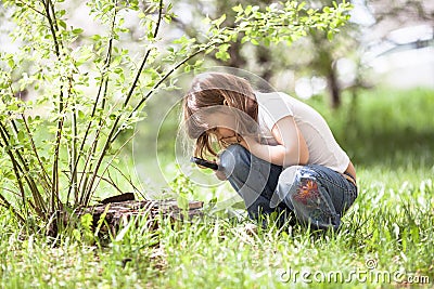 Kid girl with magnifying glass explores grass Stock Photo