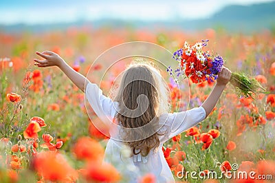 Kid girl move thru blooming field with red wild flowers Stock Photo