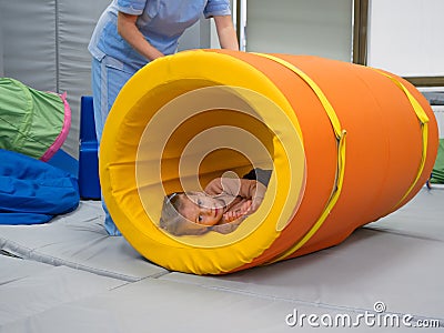 Kid girl rotation in roller tonnel during sensory integration session Stock Photo