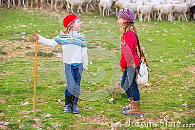 Kid girl shepherdess sisters happy with flock of sheep and stick Stock Photo
