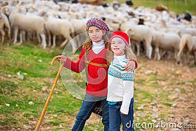 Kid girl shepherdess sisters happy with flock of sheep and stick Stock Photo