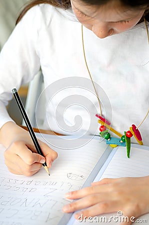 Kid girl writing alphabet sitting at the home table during corona virus lock down Stock Photo