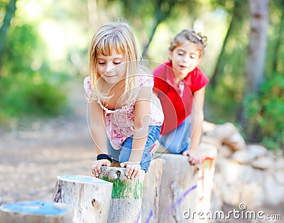 Kid girls playing on trunks in forest nature Stock Photo