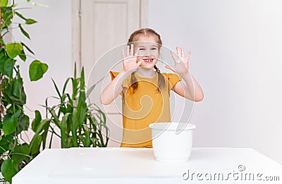 A kid grimy funny girl shows hands smeared in flour. Culinary school. Stock Photo