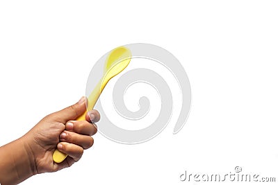 Kid hand holding yellow baby spoon Stock Photo