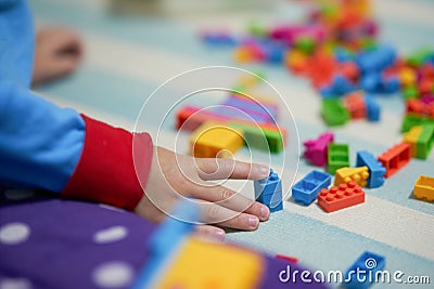 Kid hand touch colorful bricks toy on mat floor for playing Stock Photo