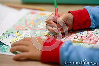 Kid hands coloring by color pencil in pajamas sleeves in covid-19 quarantine period Stock Photo