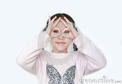 Kid with hands glasses in front of her eyes isolated on white background. Little asian girl looking through imaginary binocular Stock Photo