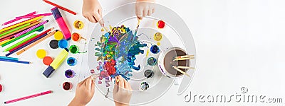 Kid hands painting at the table with art supplies. Hands with brush painting with watercolor abstract stains. Hands Stock Photo