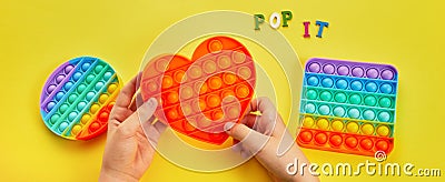 Kid hands playing with colorful pop It fidget toy. Colorful antistress sensory toy fidget push pop it. Stock Photo