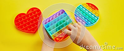 Kid hands playing with colorful pop It fidget toy. Colorful antistress sensory toy fidget push pop it. Stock Photo