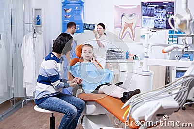 Kid holding hand on face because of pain after dentist treatment Stock Photo