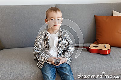 Kid holding TV remote controller. Boy without parental control watching television Stock Photo