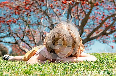 Kid laying on grass. Autumn kids, fall leaves. Stock Photo