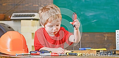 Kid learning to use screwdriver. Concentrated kid working in repairs workshop. Future occupation concept Stock Photo