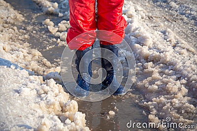 Kid legs in rainboots standing in the ice puddle Stock Photo