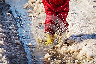Kid legs in rainboots jumping in the ice puddle Stock Photo