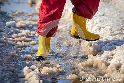 Kid legs in rainboots running in the ice puddle Stock Photo