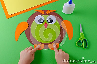 Kid is making a owl with color paper, glue and scissors Stock Photo