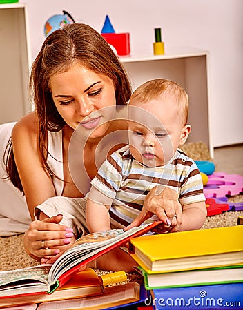 Kid with mother baby boy lying on floor and read book. Stock Photo
