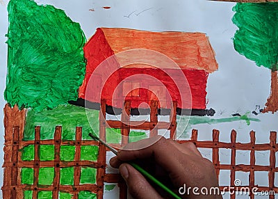 Kid painting a beautiful scenery of hut, trees and green grass holding paint brush in hand Stock Photo