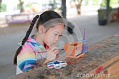 Kid painting, Portrait little child girl intend to paint on earthenware dish Stock Photo