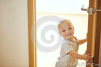 Kid peeking out looking on camera of open room door Stock Photo