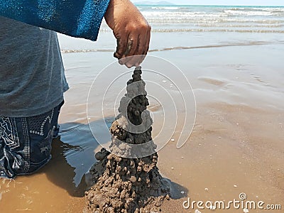 Kid playing on the black sand beach creating and building sandcastle in summertime Stock Photo