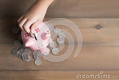 Kid put coin to piggy bank on the vintage wood Stock Photo