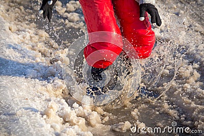 Kid in rainboots jumping in the ice puddle Stock Photo