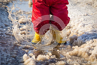 Kid in rainboots jumping in the ice puddle Stock Photo