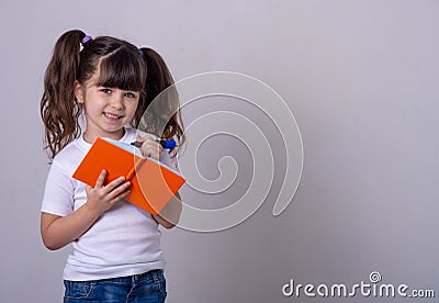 Surprised cute child writing in notebook using pencil, keeping mouth wide open. Four or five years old kid, isolated Stock Photo