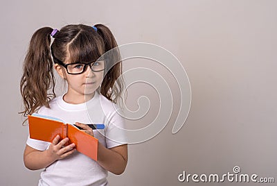 Surprised cute child in eyeglasses, writing in notebook using pencil, keeping mouth wide open. Four or five years, isolated Stock Photo