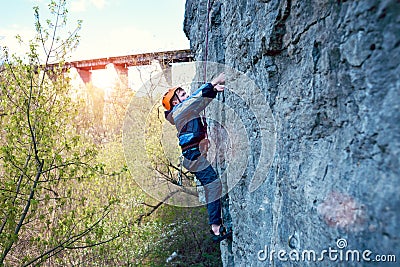 Kid rock climber climbs the cliff. Stock Photo