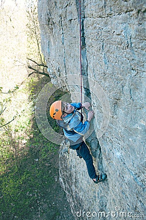 Kid rock climber climbs the cliff. Stock Photo