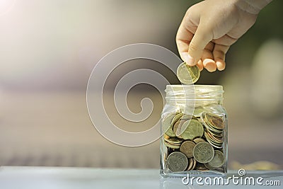 Kid saving coin in glass piggy bank Stock Photo