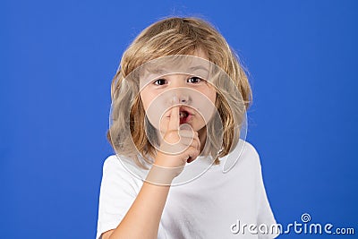 Kid with show no talk gesture. Boy with shows shh sign. Be quiet. Hush dont tell. Child put finger to lips mouth, ask Stock Photo