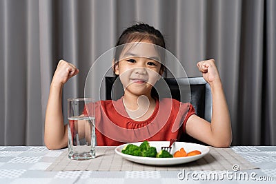 Kid shows strength of eats vegetables and nutritious food Stock Photo