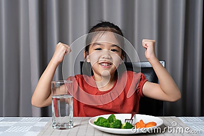 Kid shows strength of eats vegetables and nutritious food Stock Photo