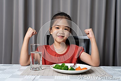 Kid shows strength of eats vegetables and nutritious food Stock Photo