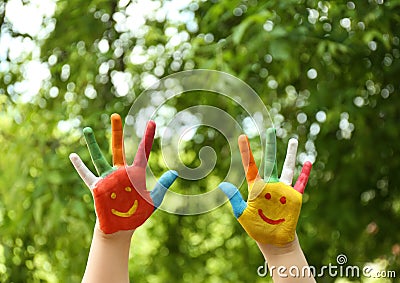 Kid with smiling faces drawn on palms in park, closeup Stock Photo