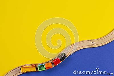 Toy train and wooden rails on yellow and blue color background Stock Photo