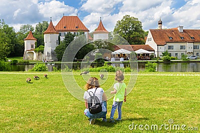 Kid walks on green meadow by old Blutenburg Castle, Munich, Germany Stock Photo